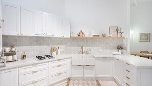 A modern kitchen with white cabinetry, a central island, and a built-in sink. - Waterfront Getaway, Kayaks included in stay - Kid Friendly (Sanctuary Point)