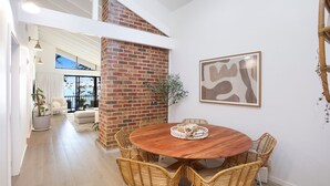 A dining area with a brick column, wicker chairs, and a wooden table. - Waterfront Getaway, Kayaks included in stay - Kid Friendly (Sanctuary Point)