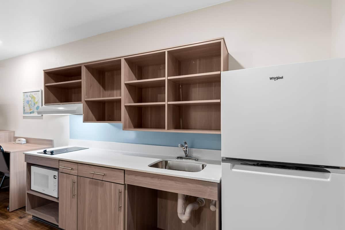 Una cocina moderna con microondas integrado, un lavamanos y un refrigerador blanco.