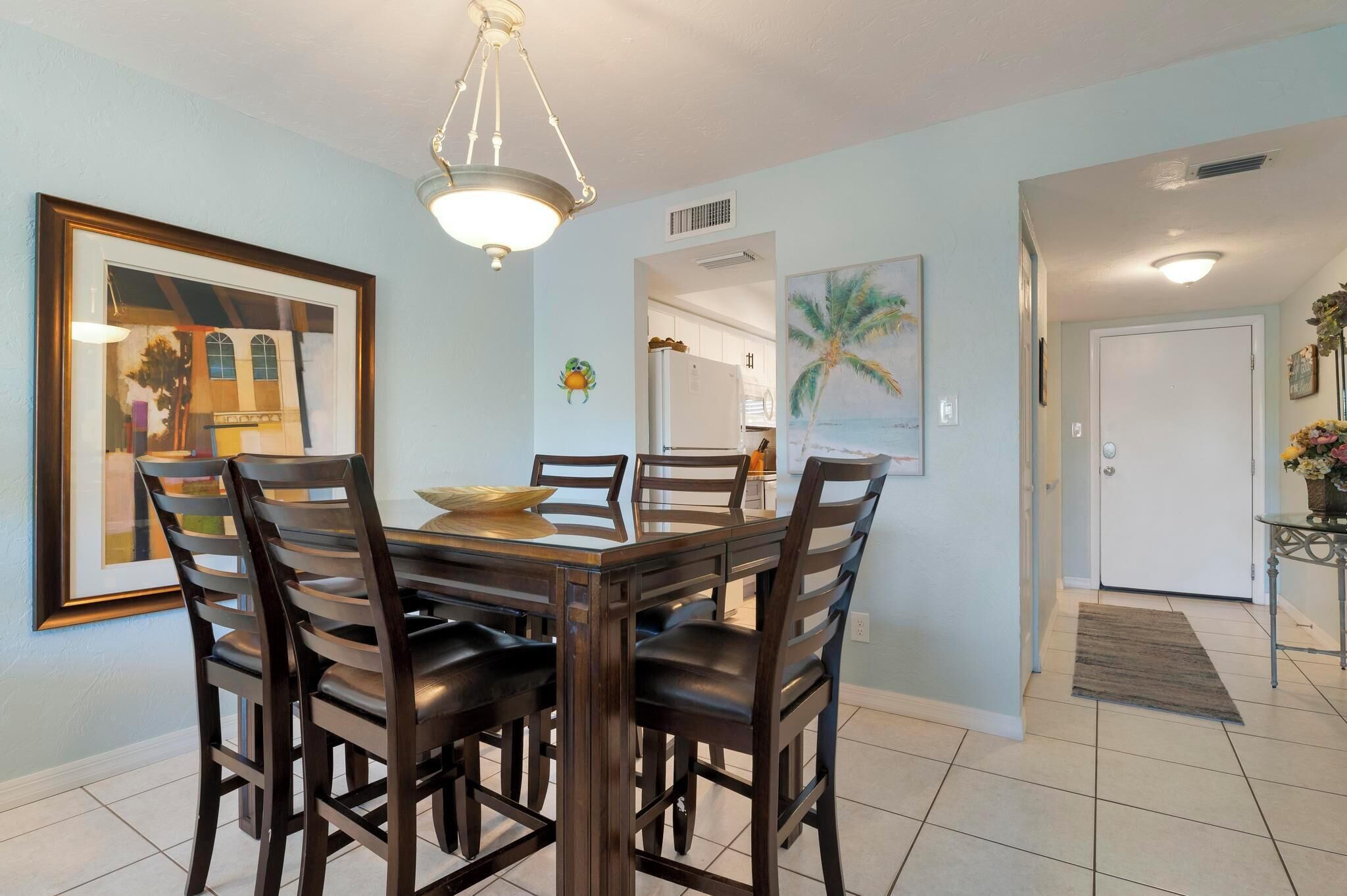 A dining area with a wooden table and chairs, a framed picture on the wall, and a door leading to another room.