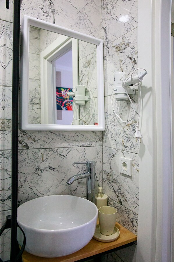 A bathroom with a white sink, a mirror, and a marble-patterned wall.