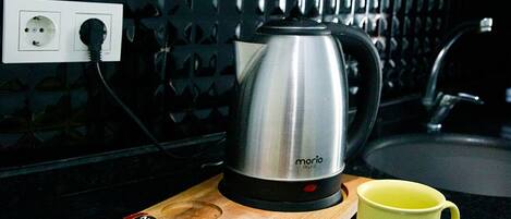 A kitchen counter with a coffee maker, a mug, and a cutting board with food items.