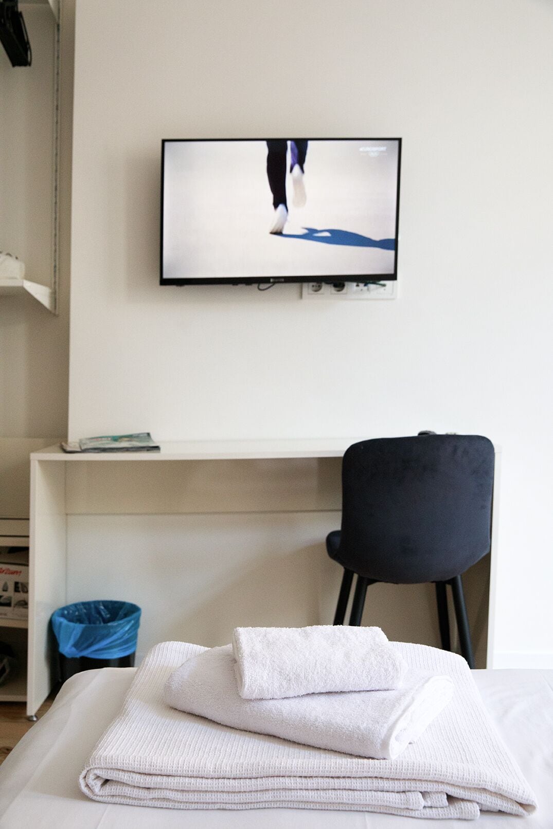 Una camera d'albergo con un letto, una televisione a parete, una scrivania e una sedia.