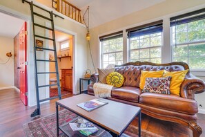 A living room with a brown leather sofa, a coffee table, and a ladder leading to an upper floor.