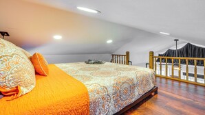 Un dormitorio con una cama grande, cabecera de madera y balcón con barandilla.