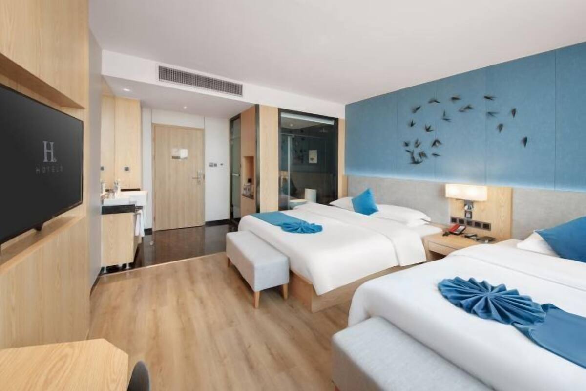 A hotel room with two beds, a desk, and a TV.