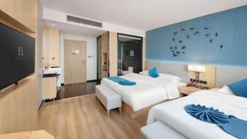 A hotel room with two beds, a desk, and a TV.