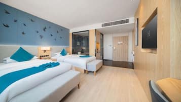 A hotel room with two beds, a large mirror, a wooden floor, and a wall with a bird mural.