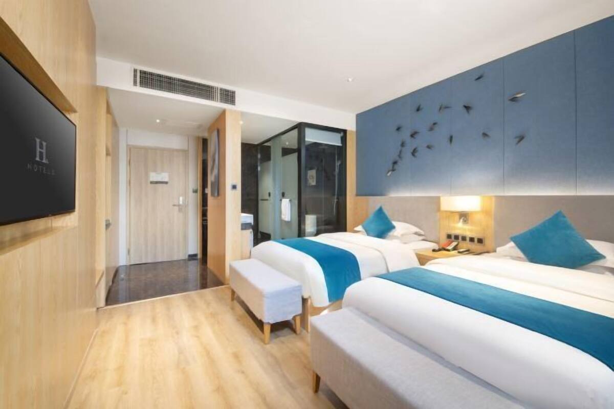 A modern hotel room with two beds, a TV, and a wall-mounted artwork.
