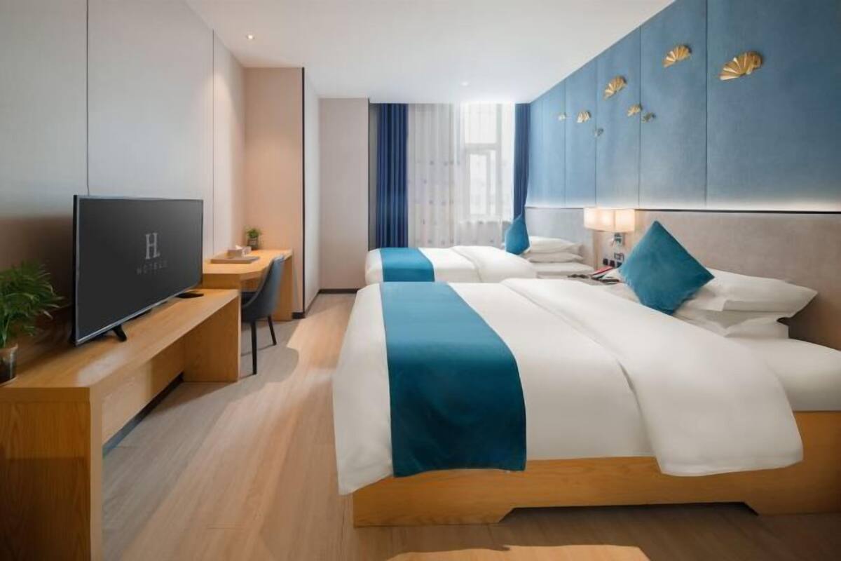 A modern hotel room with a large bed, a desk, and a television.