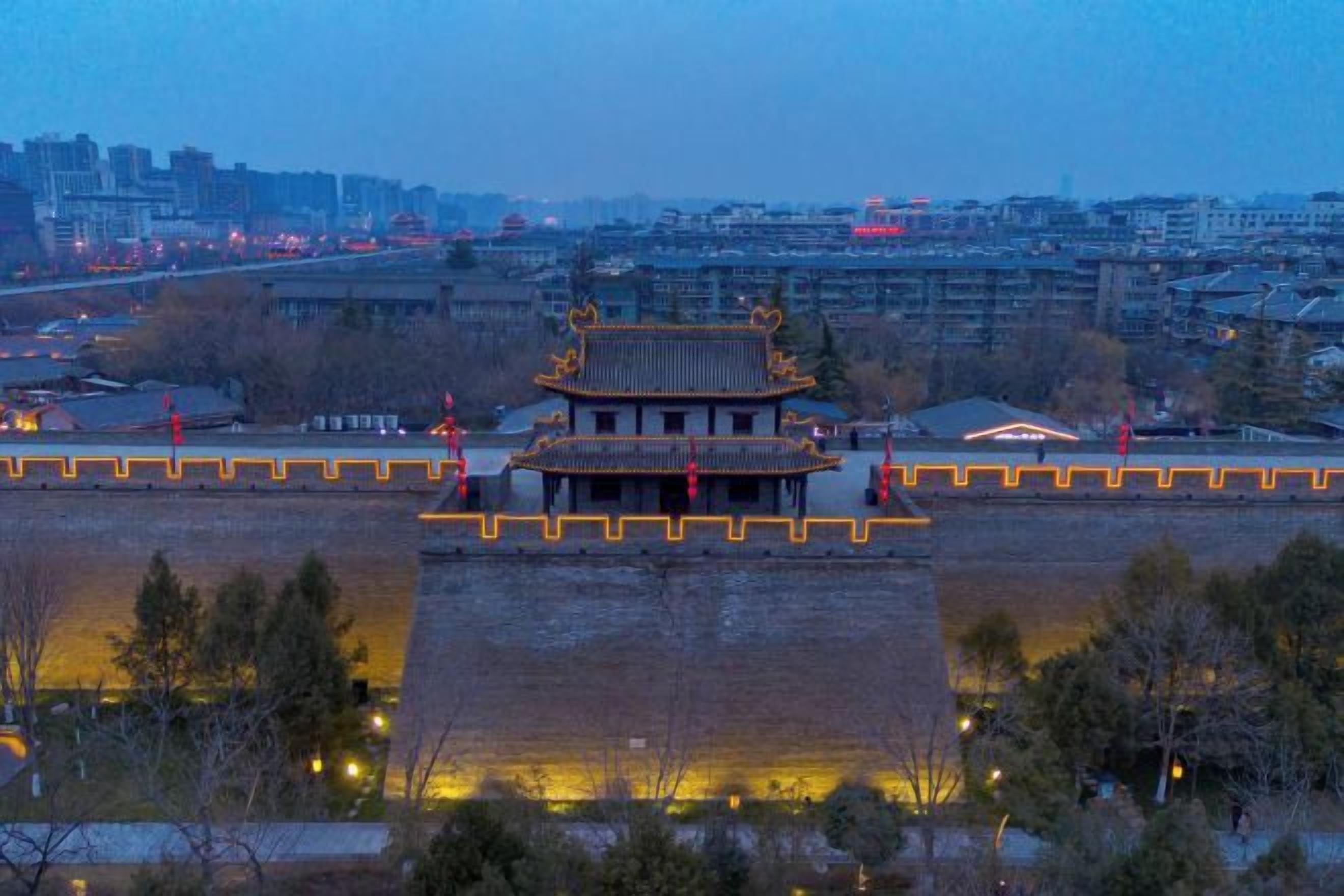 A traditional building with a central courtyard, surrounded by a wall with evenly spaced lights.