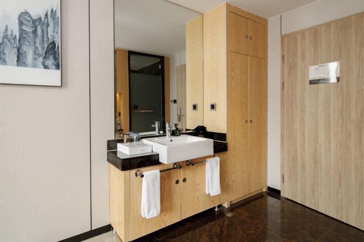 A modern bathroom with a wooden vanity, a large mirror, and a white sink.