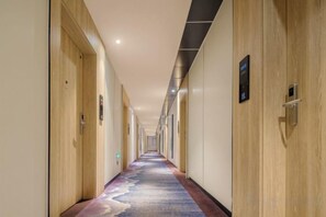 A hotel hallway with wooden doors, a carpeted floor, and a ceiling with recessed lighting. - H Hotel (Xi'an Bell and Drum Tower Nanmenwai Northwest University Shuijing) (Xi'an)