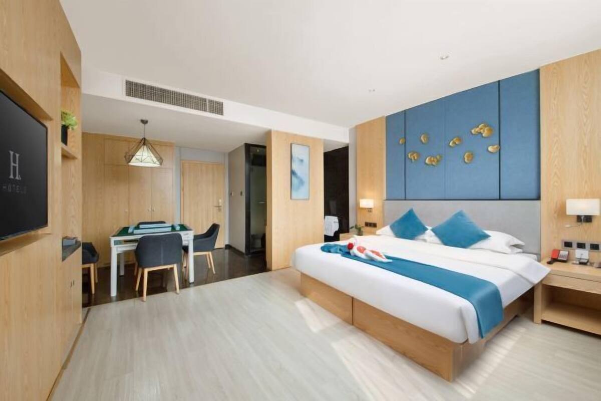 A hotel room with a bed, desk, chair, and a TV.