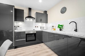 A modern kitchen with a built-in oven, a microwave, a coffee maker, and a clock on the wall.