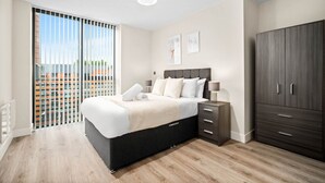 Un dormitorio moderno con una cama grande, un armario, una mesita de noche y vistas a través de una puerta corredera.