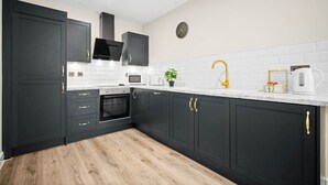A modern kitchen with dark cabinets, a microwave, a toaster, and a coffee maker.
