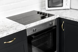 Una cocina con tope de inducción negro, microondas y horno empotrado.