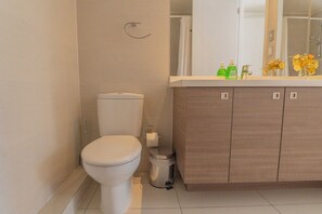 Een moderne badkamer met toilet, wastafel met spiegel en toiletartikelen op het aanrecht.