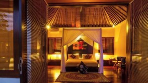 A room with a bed, a nightstand, and a window with blinds. - Imani Villas Bali (Bali)