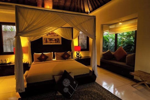 A four-poster bed with a canopy, a sofa, a small table, and a nightstand with a lamp. - Imani Villas Bali (Bali)