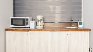 A kitchen with a microwave, coffee maker, and a sink with a faucet.