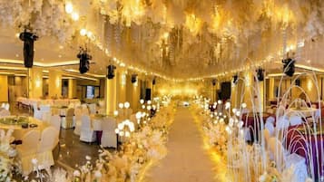 A banquet hall with round tables, chairs, and a central aisle.