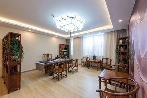 Una habitación con mesa de billar, sillas de madera, una estantería y un candelabro.