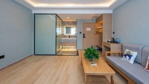 Una sala de estar moderna con una mesa de centro de madera, un sofá y un separador de vidrio que conduce a una zona de cocina.