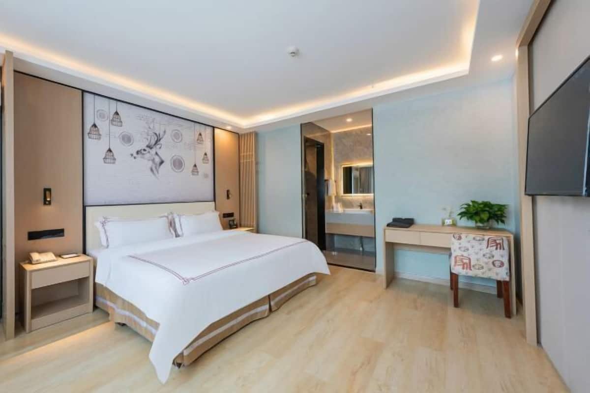 Una habitación de hotel moderna con una cama grande, mesitas de noche, un escritorio y un espejo.