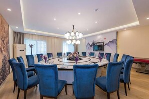 Un comedor moderno con una mesa redonda, sillas azules y una lámpara de araña.