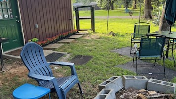A backyard with a fire pit, outdoor seating, and a wooden shed.