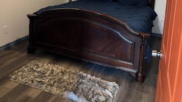 A bedroom with a wooden bed, a ceiling fan, a framed artwork, and a rug.