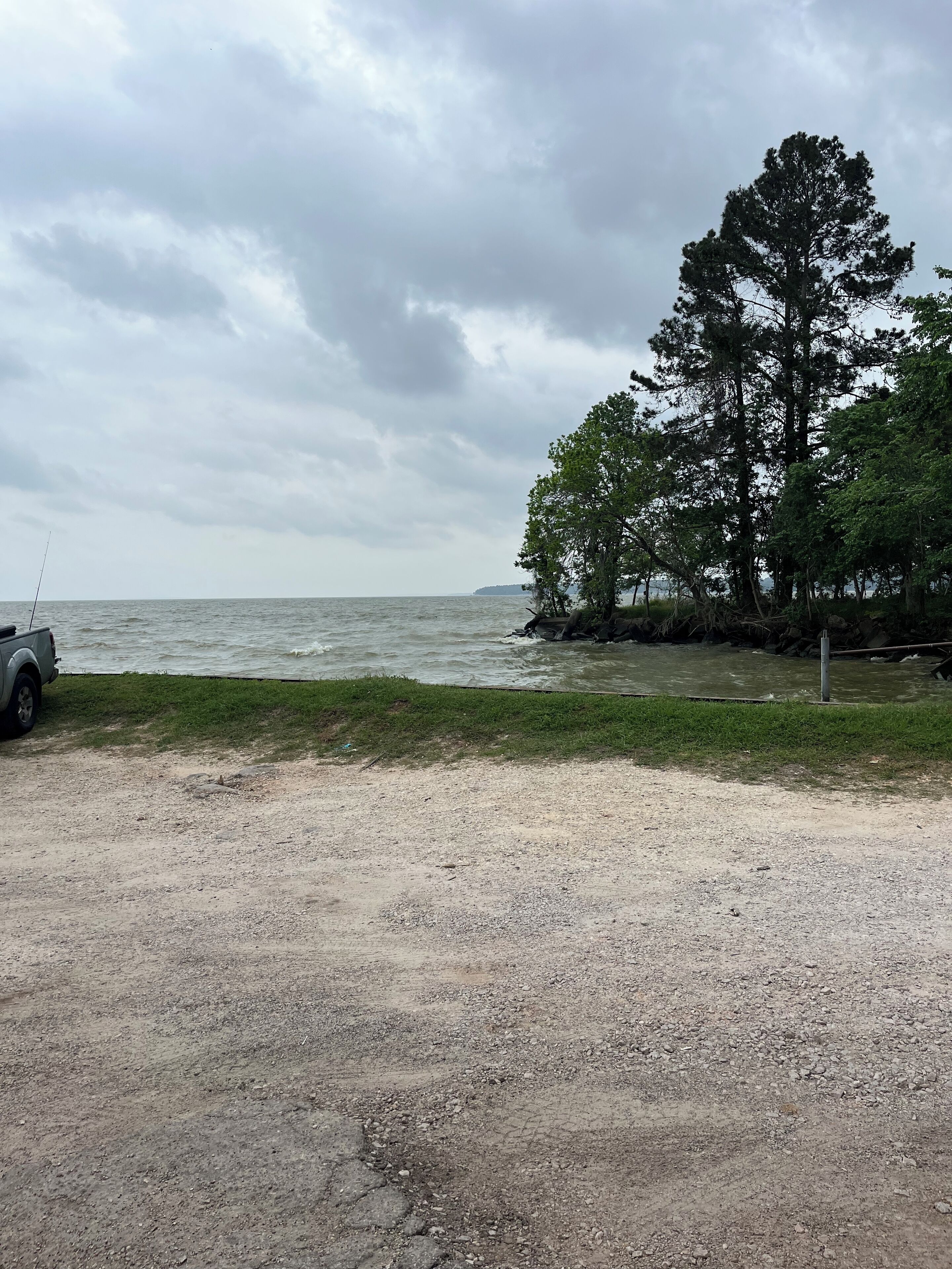A gravel area with a parked vehicle and a large tree.