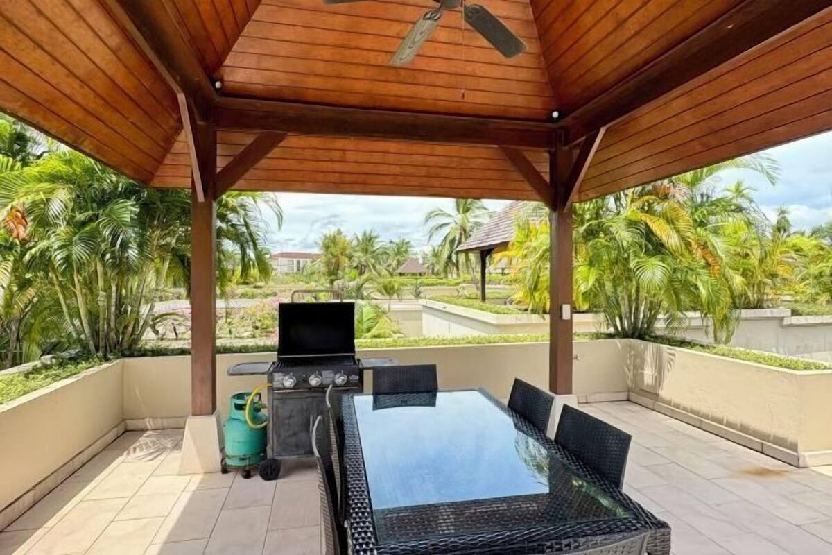 Un patio al aire libre techado con una parrilla, una mesa y sillas.