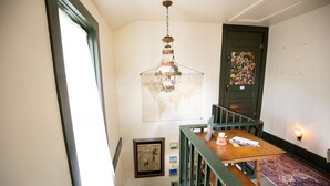 Eine Treppe mit Holzwand, eine hängende Chandelierleuchte, eine Weltkarte an der Wand und eine Tür mit einem Buntglasfenster.