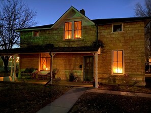 A stone house with a porch, a front door, and a small garden area. - Buffalo Haus: Entire House, Welcoming Historic Limestone House Downtown (Hays)