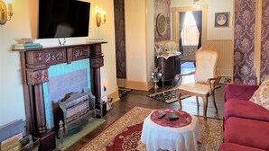 Ein Wohnzimmer mit Kamin, Fernseher und einem roten Sofa.