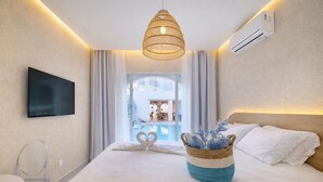 Habitación de hotel moderna con una cama grande, un televisor montado en la pared, una lámpara de techo y vistas al área de la piscina.