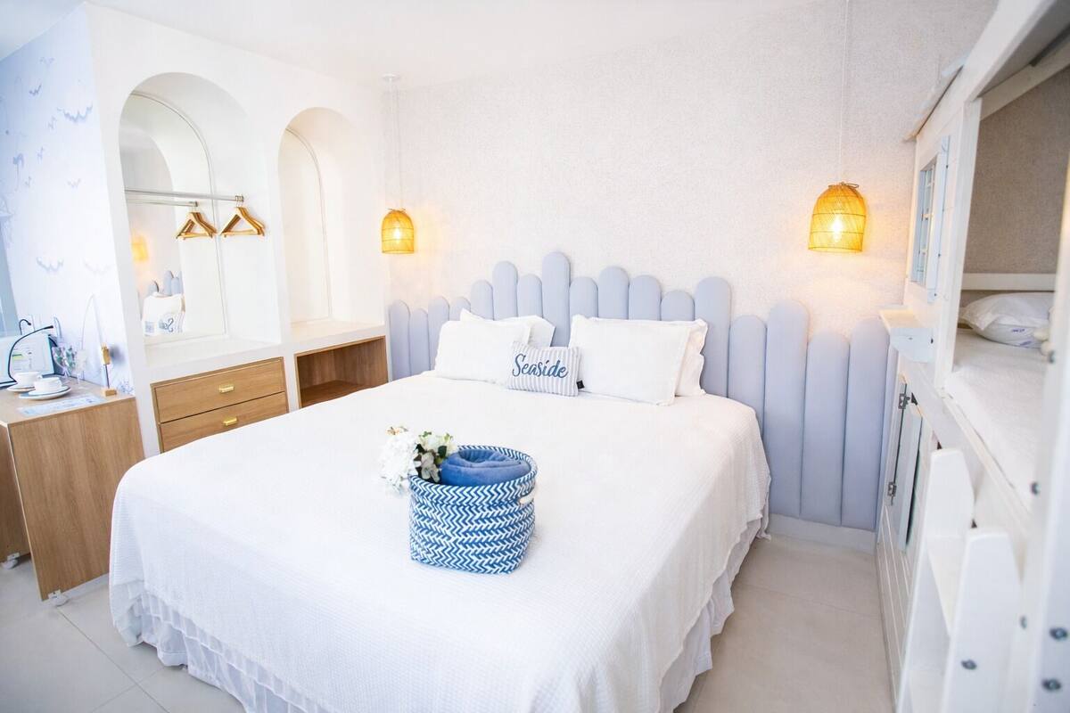 Habitación de hotel ordenada con cama, mesitas de noche, cómoda y espejo.