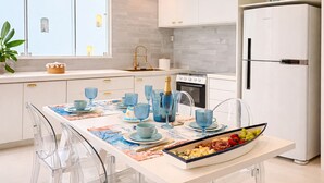 Una cocina moderna con armarios blancos, horno integrado y refrigerador.