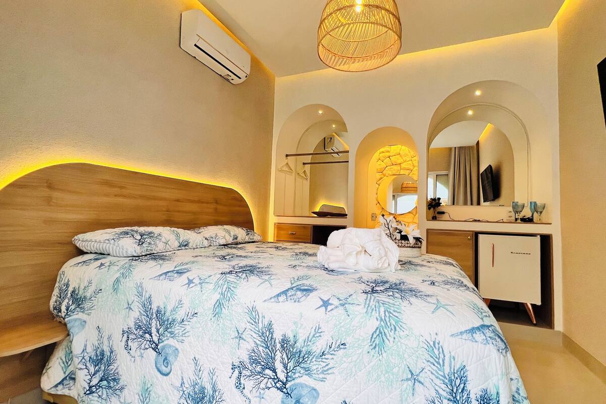 Un dormitorio con cama, escritorio, espejo y aire acondicionado.