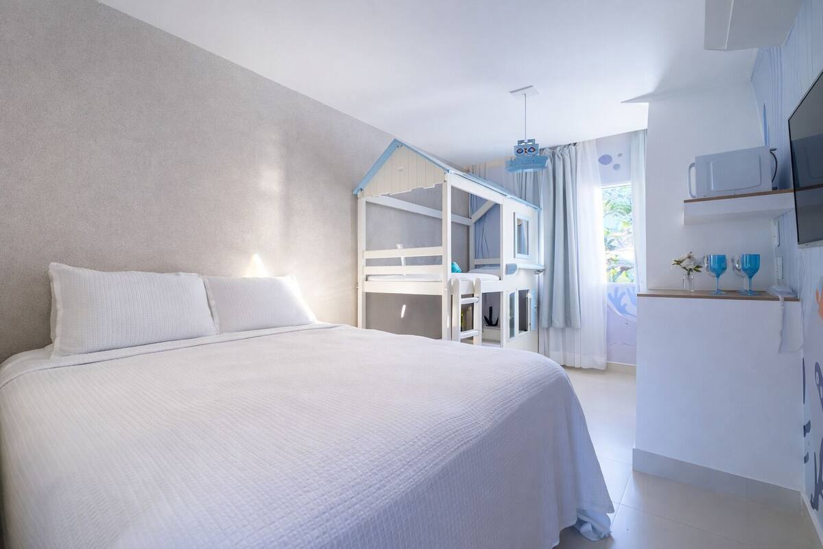 Un dormitorio con cama, literas y una kitchenette.