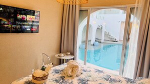 Habitación de hotel con vista a una piscina, una mesita con tazas y una cesta decorativa.