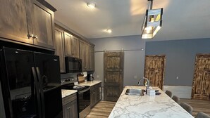 Una cocina moderna con armarios oscuros, encimera de mármol y una isla central con asientos.