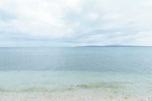 Vista de una playa con agua cristalina y una masa de tierra a lo lejos.