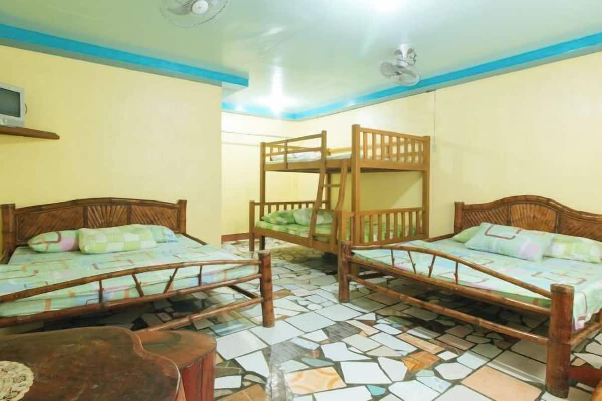 A room with three bunk beds, a television on the wall, and a tiled floor.