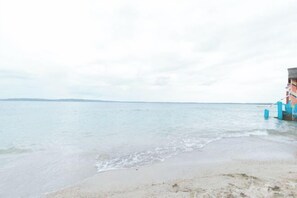 A beach with a building in the background. - RGV Beach Resort Batangas RedPartner (Calatagan)