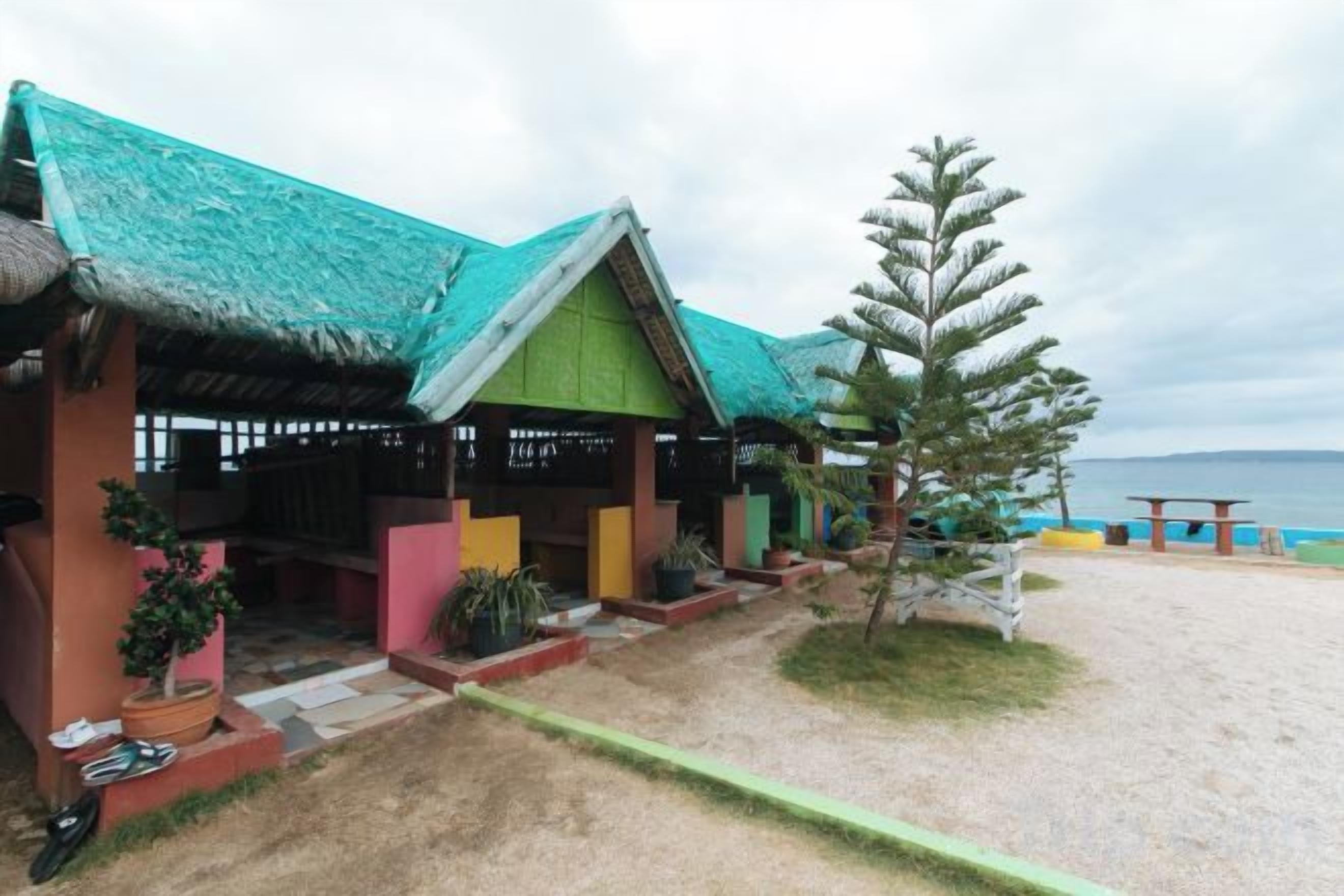 A beachside building with a thatched roof, a covered outdoor seating area, and a view of the sea.