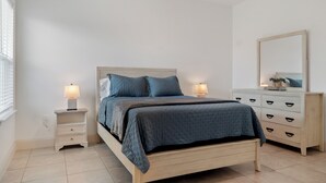 Ein Schlafzimmer mit Bett, Nachttischen, einem Schminktisch und einem Spiegel.